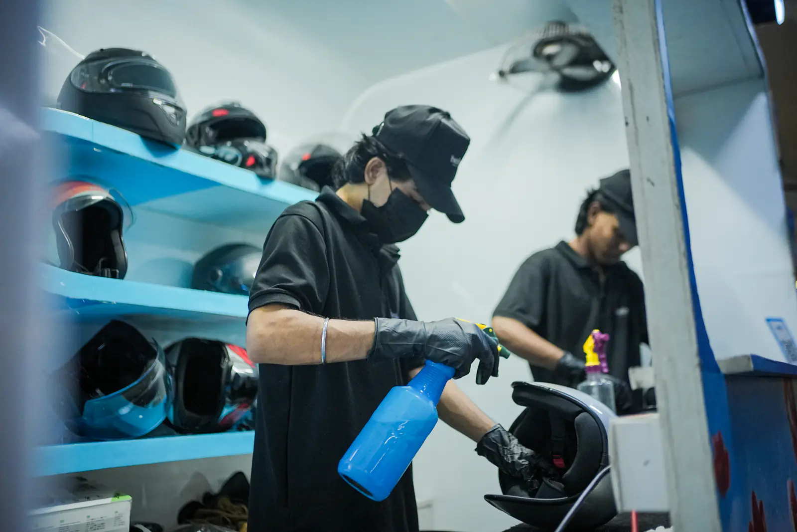 Helmets lined up on Helmate's shelves while the crew works behind them