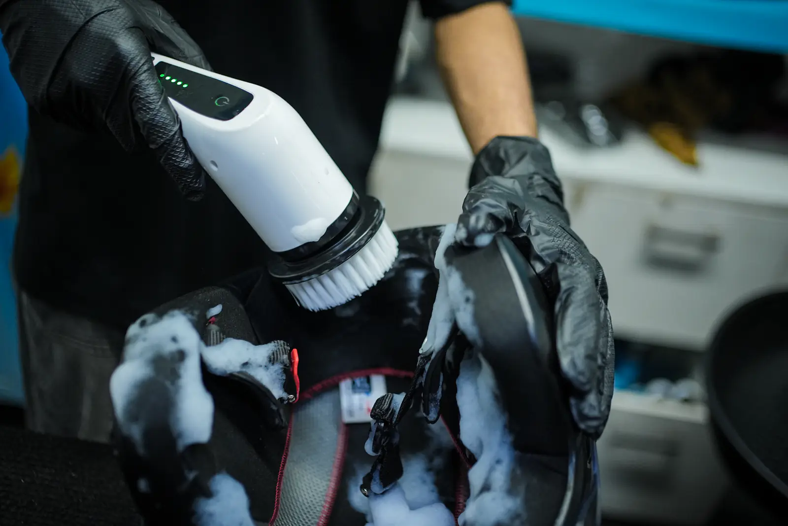 Close-up of a padded helmet liner being scrubbed with foam and a rotary brush
